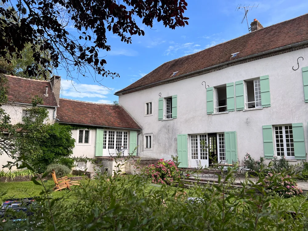 Le Couvent côté jardin : façade blanche, volets vert d'eau, terrasse et hortensias