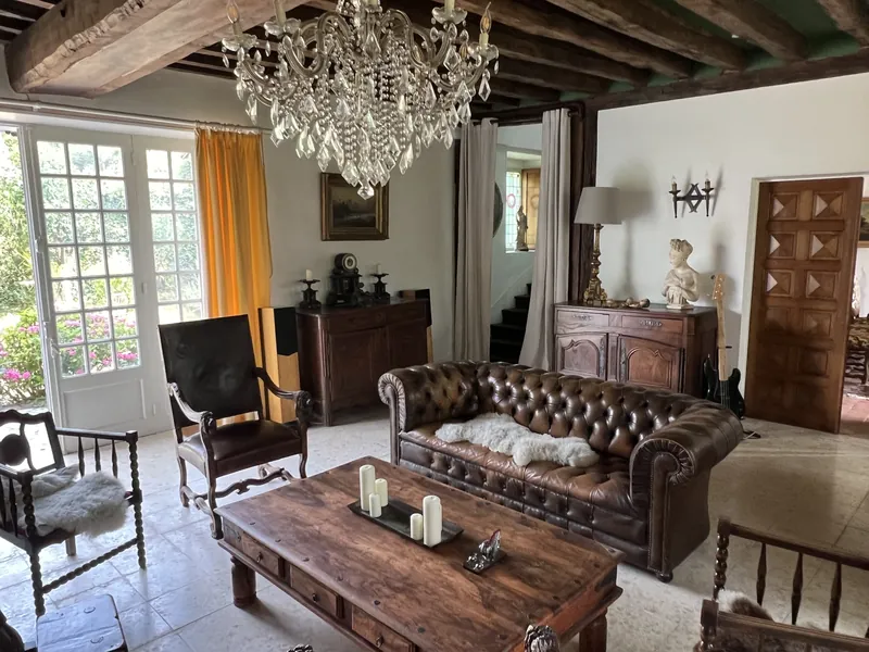 Le grand salon : poutres, lustre en cristal et canapé Chesterfield