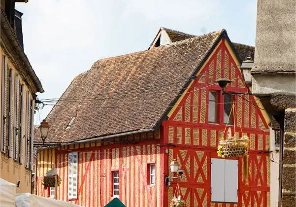Étals du marché de Toucy devant une maison à pans de bois rouges