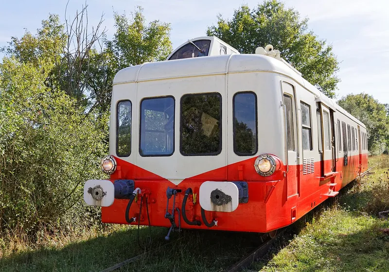 L'autorail rouge et crème du train touristique de Puisaye au milieu de la végétation